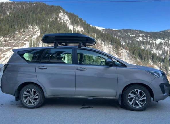 Overlanding vehicle equipped with roof rack, roof box, and outdoor adventure accessories in a mounta